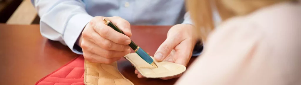 Chiropraktiker zeigt Patientin eine sensomotorische Einlage zur Unterstützung bei Rückenproblemen in Bayern