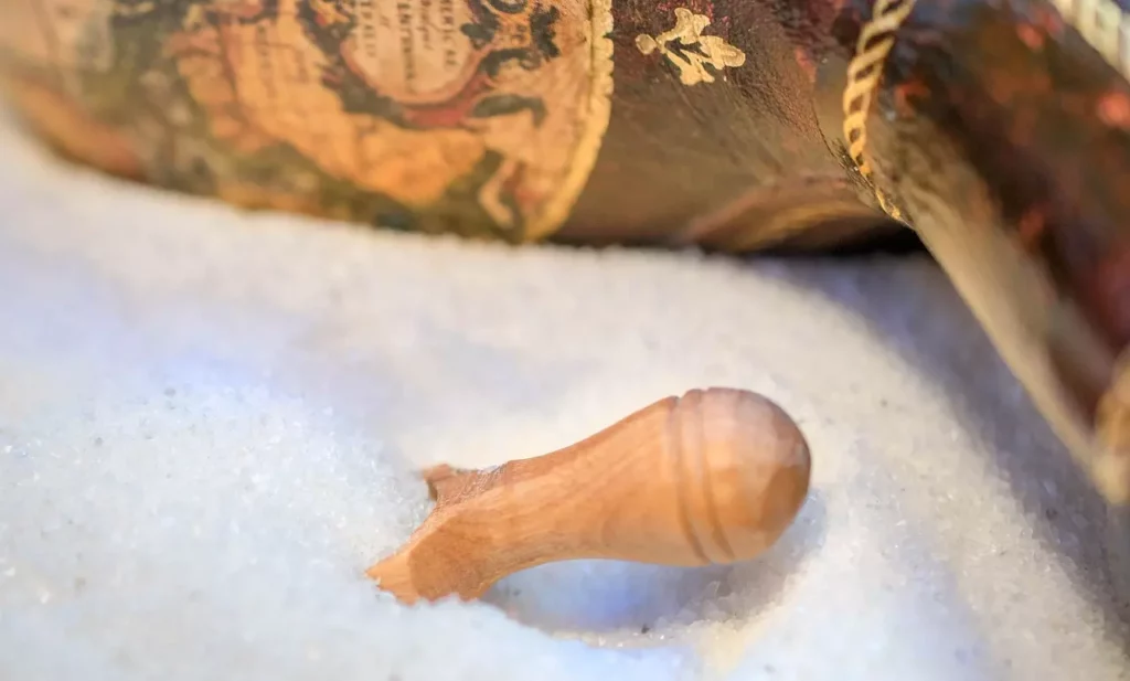 Nahaufnahme eines Holzstempels im weißen Salz mit einem antik aussehenden Buch im Hintergrund