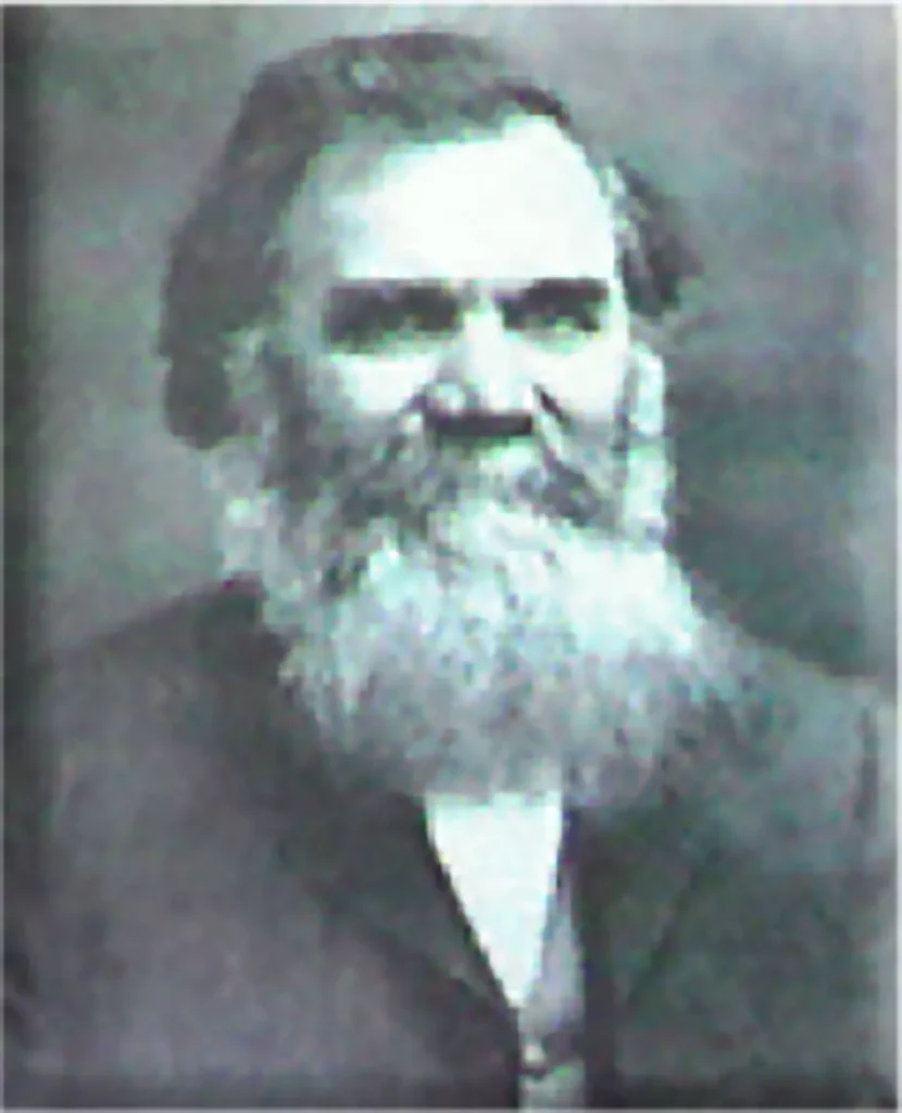 Schwarz-weiß-Porträt eines älteren Mannes mit langem Bart und dunklem Anzug vor neutralem Hintergrund